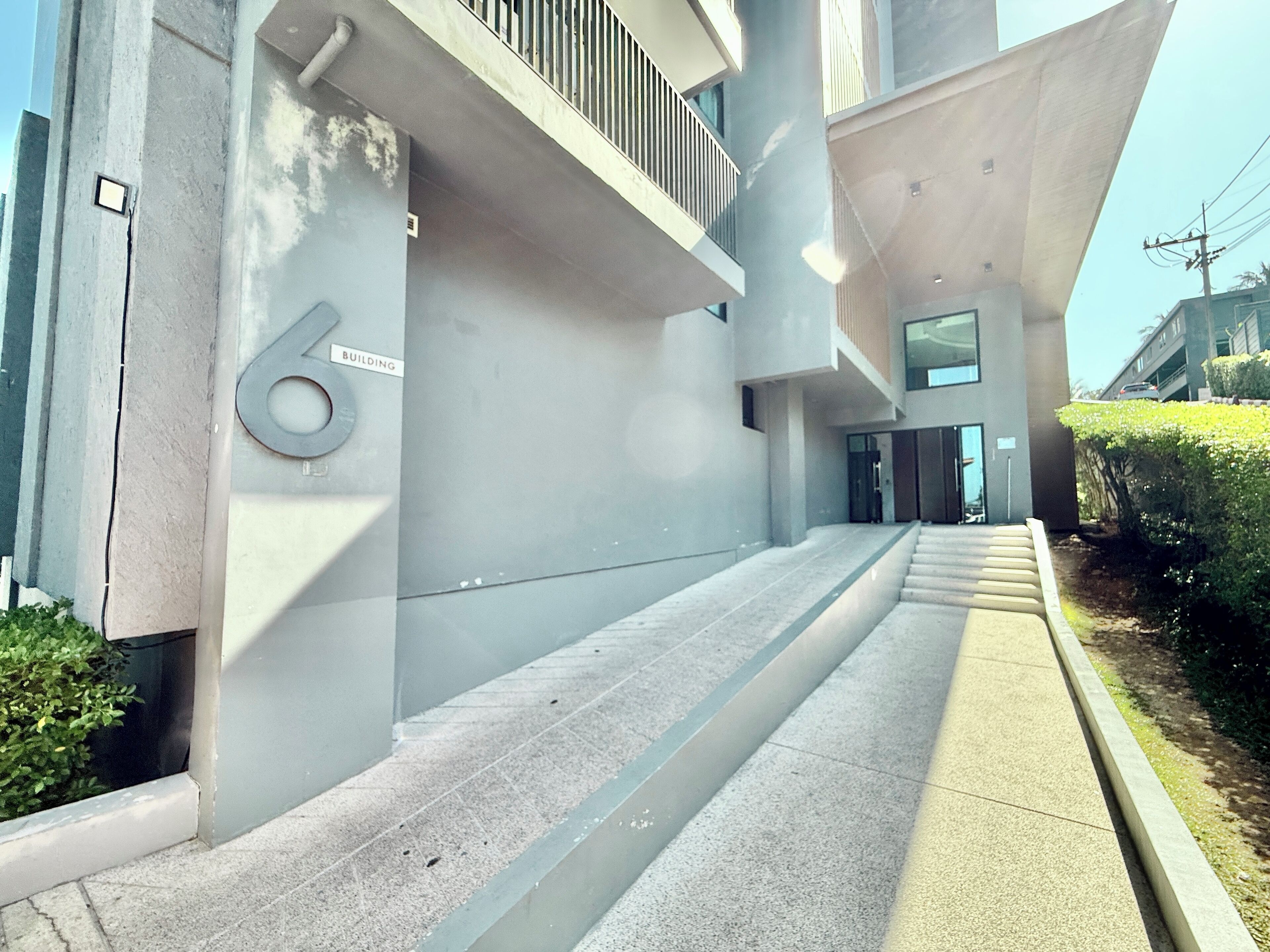 A modern building with a staircase leading to a door marked '6'.
