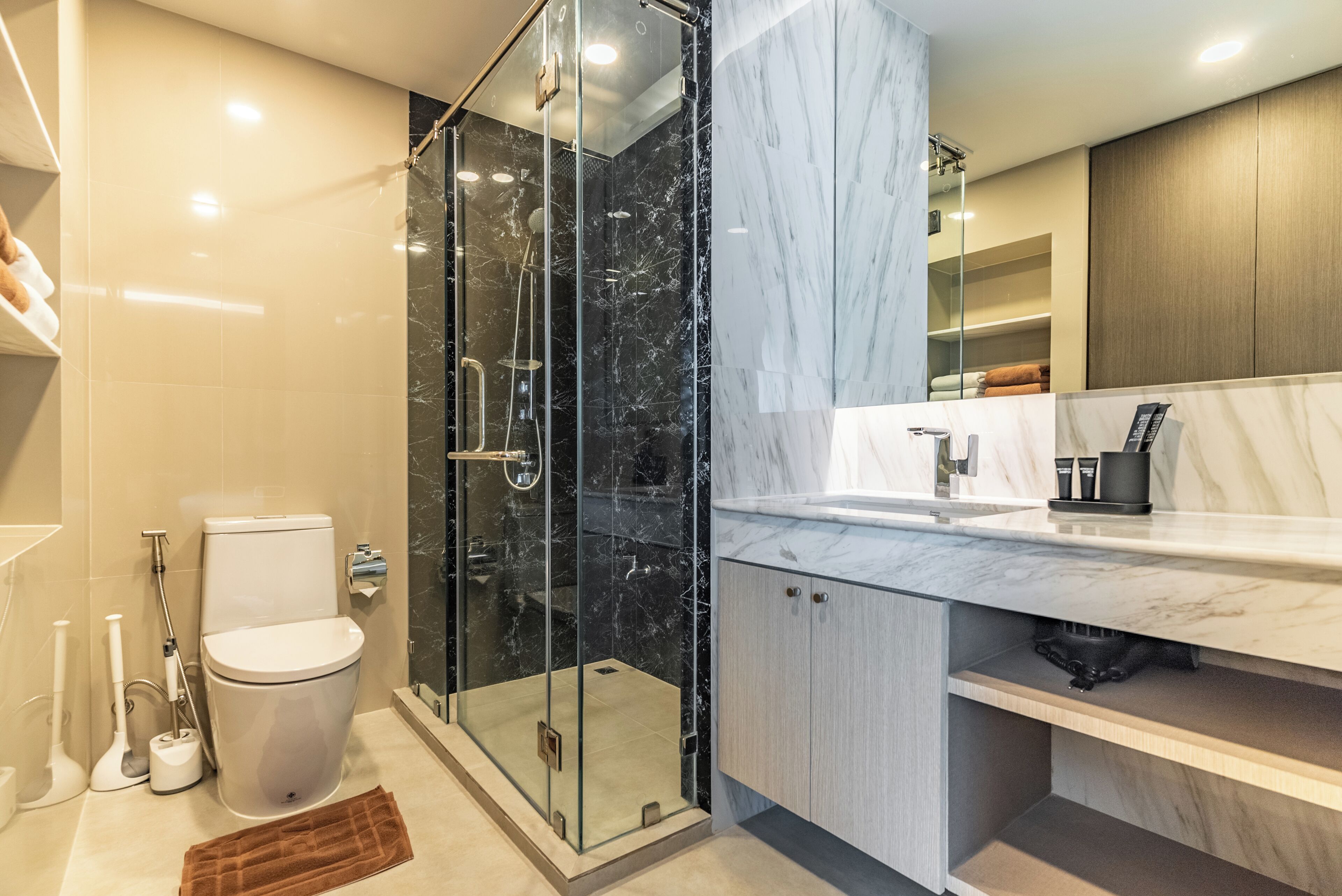 A modern bathroom with a glass-enclosed shower, a white toilet, and a marble countertop sink.