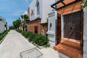 A residential street with houses featuring brick and white facades, a red door, and a gated entrance. - Panora Villa 8112 By Villacarte (Choeng Thale)