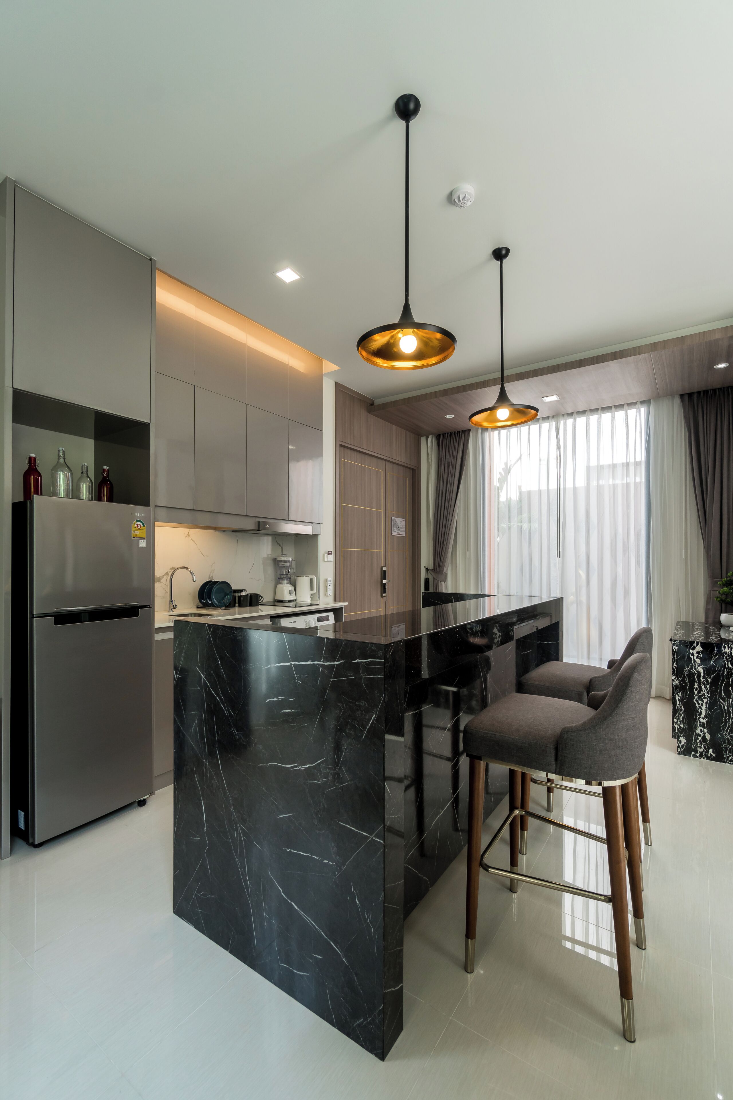 Una cocina moderna con una isla central, electrodomésticos de acero inoxidable e iluminación colgante.