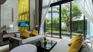 Ein modernes Wohnzimmer mit einem grauen Sofa, gelben Kissen, einem schwarzen Marmor-Couchtisch und einem Flachbildfernseher an der Wand.