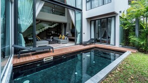 Ein modernes Haus mit Swimmingpool, großen Fenstern und einer Treppe, die zu einer oberen Ebene führt.