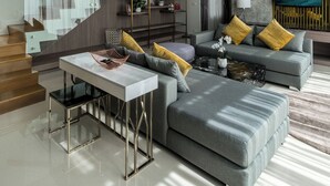Ein modernes Wohnzimmer mit grauem Sofa, einem Couchtisch und einer Treppe, die in eine obere Ebene führt.