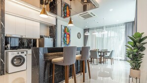 A modern kitchen with a built-in washer, marble countertops, and pendant lighting. - Panora Villa 8119 By Villacarte (Choeng Thale)