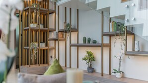 A modern interior with a wooden bookshelf, a small potted plant, and a glass railing. - Panora Villa 8119 By Villacarte (Choeng Thale)