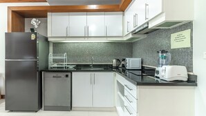 Una cocina moderna con armarios blancos, un refrigerador negro, un lavavajillas, un microondas y un tostador.