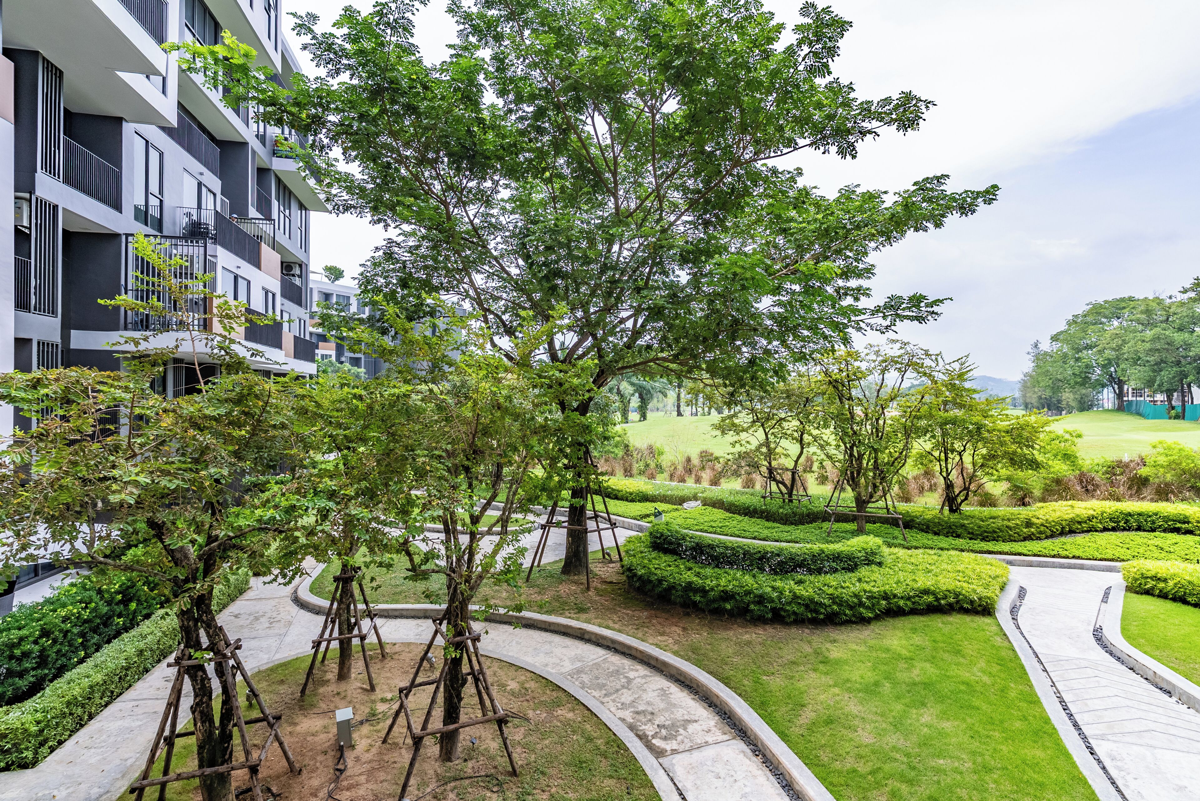 A residential building with a landscaped garden, curved pathways, and neatly trimmed hedges.