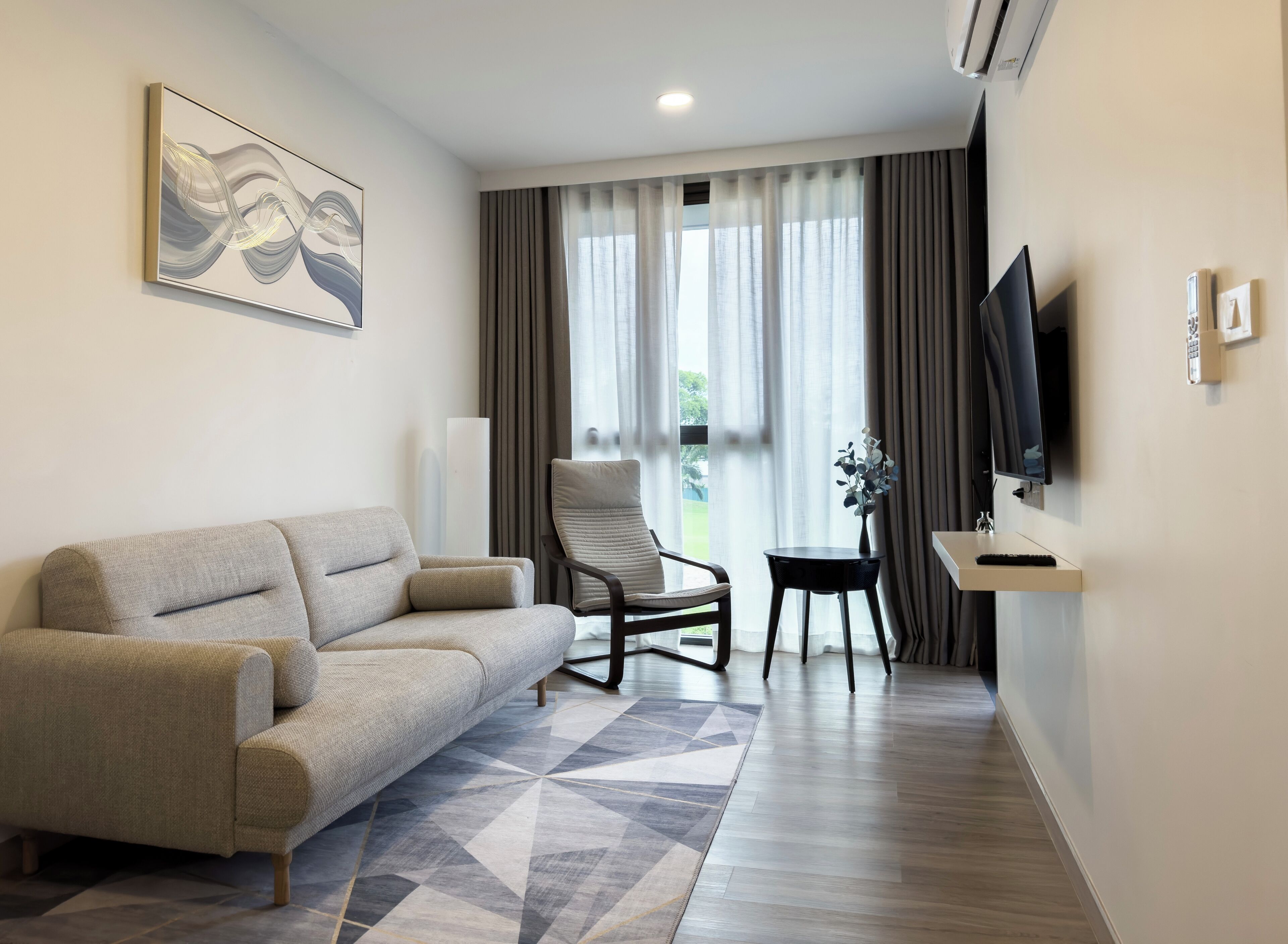 A modern living room with a sofa, a chair, a small table, a TV, and a window with curtains.