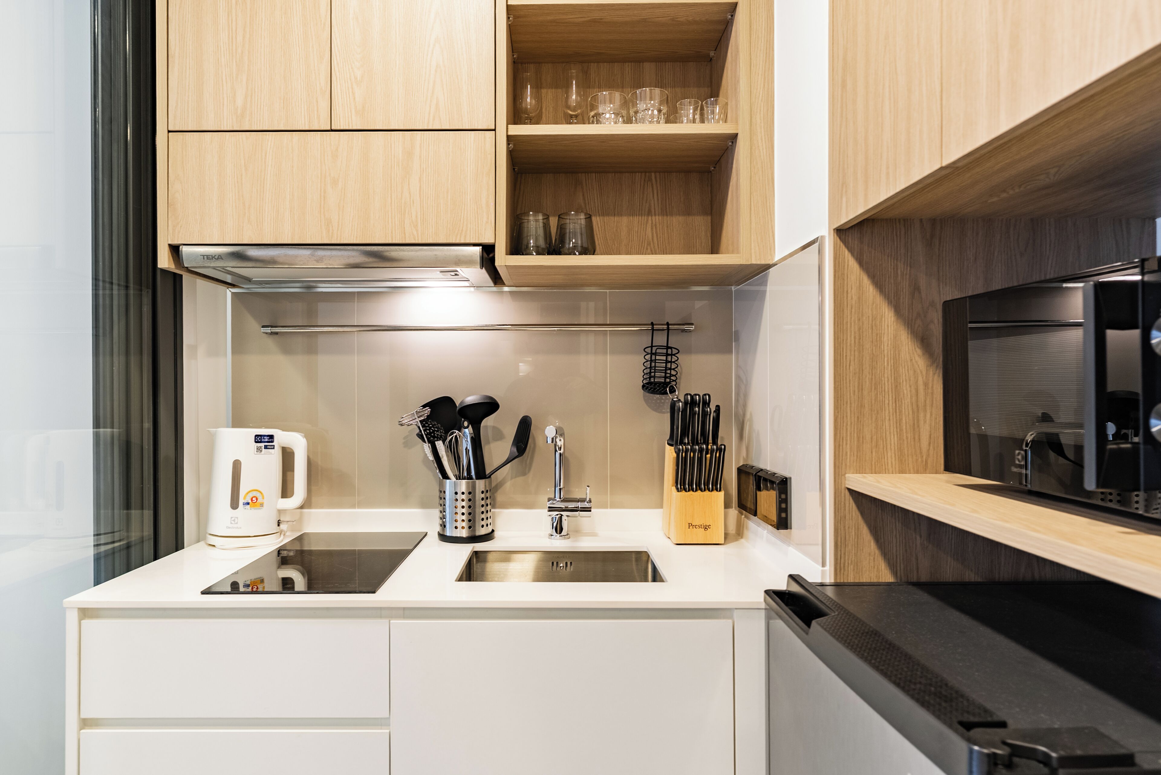 Une cuisine moderne avec des meubles en bois, un évier en acier inoxydable et un micro-ondes noir.