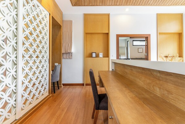 A modern dining area with a wooden table, a chair, and a decorative white partition. - Tanode Villa 511 By Villacarte (Choeng Thale)