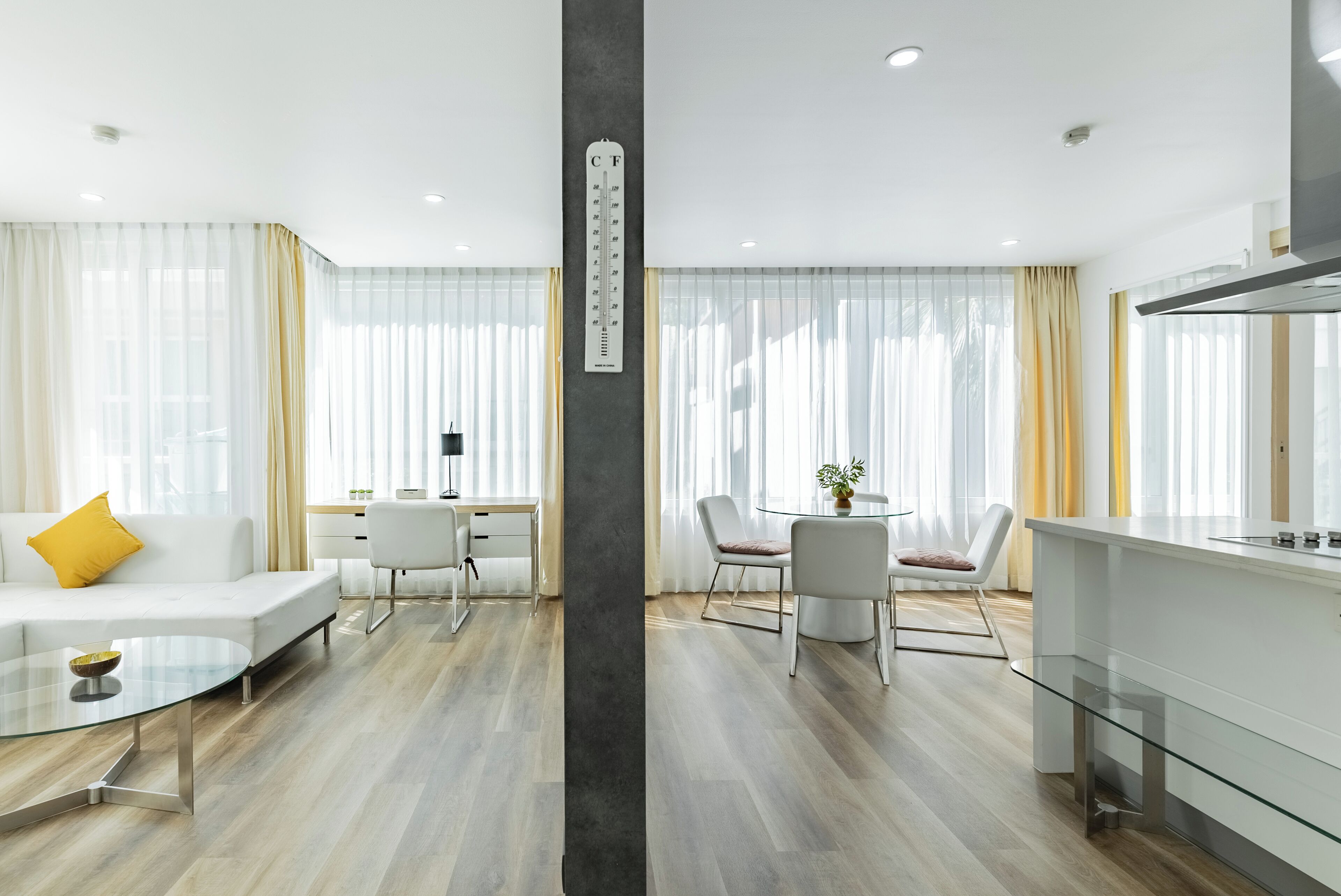 Una sala moderna con un sofá, una mesa de centro de vidrio y una zona de comedor con sillas y una mesa.