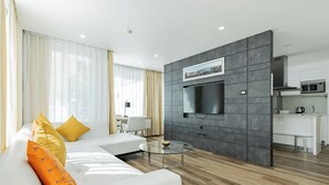 Un salon moderne avec un canapé, une table basse en verre et un téléviseur fixé au mur, qui est de couleur grise.