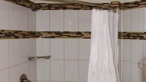 Une salle de bain avec une douche, des toilettes et un carrelage au sol.