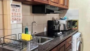 Une cuisine avec des meubles en bois, un évier en acier inoxydable, un four à micro-ondes et un lave-linge.