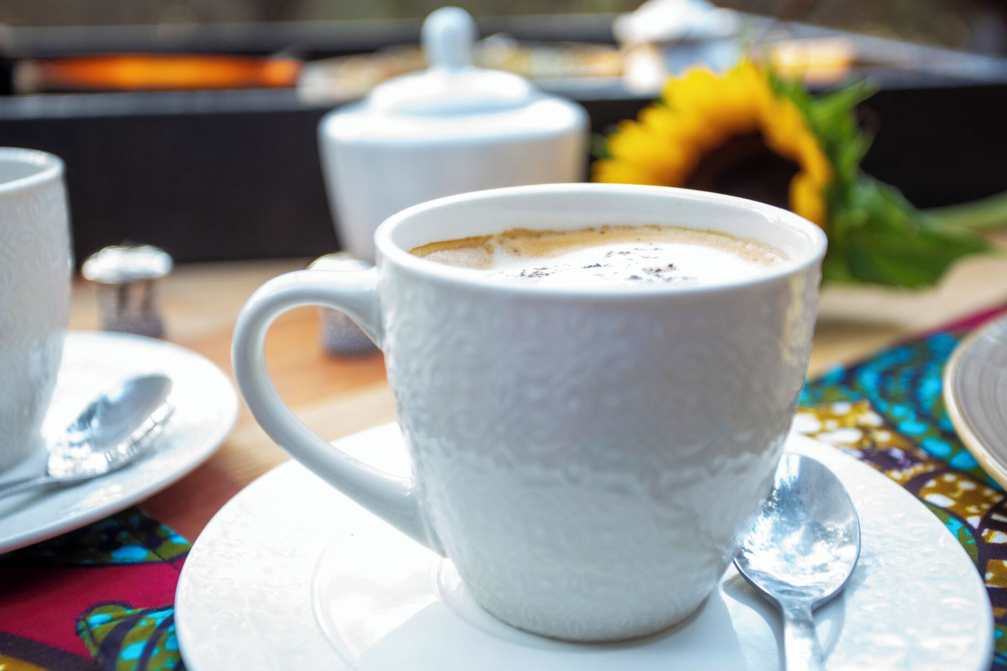 A white ceramic mug with a textured surface, placed on a white saucer with a spoon beside it.