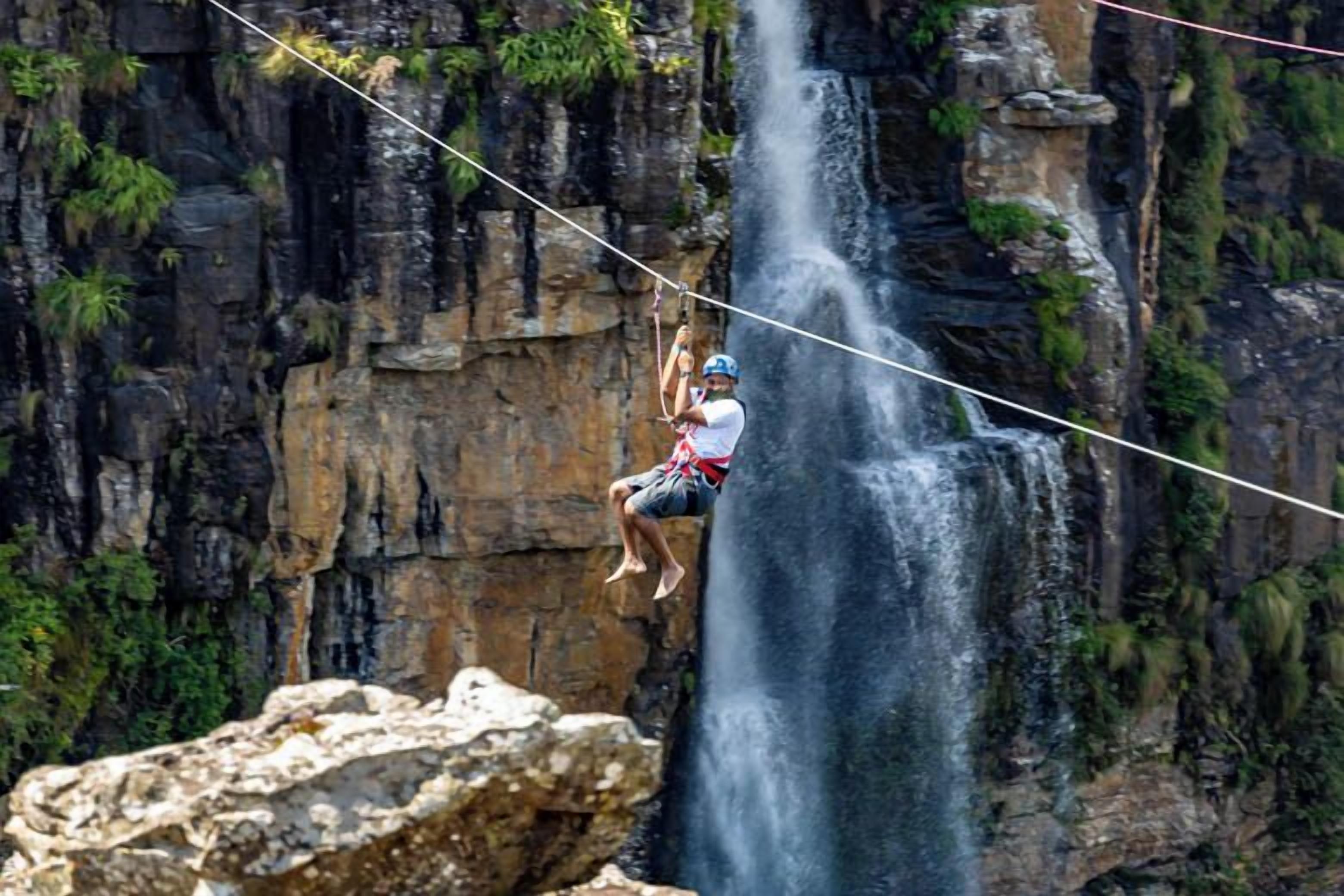 A person rappelling down a waterfall with a rope.