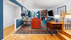 Un salon spacieux avec un mur d’accent bleu, une cheminée, un ensemble de canapés et une table basse.