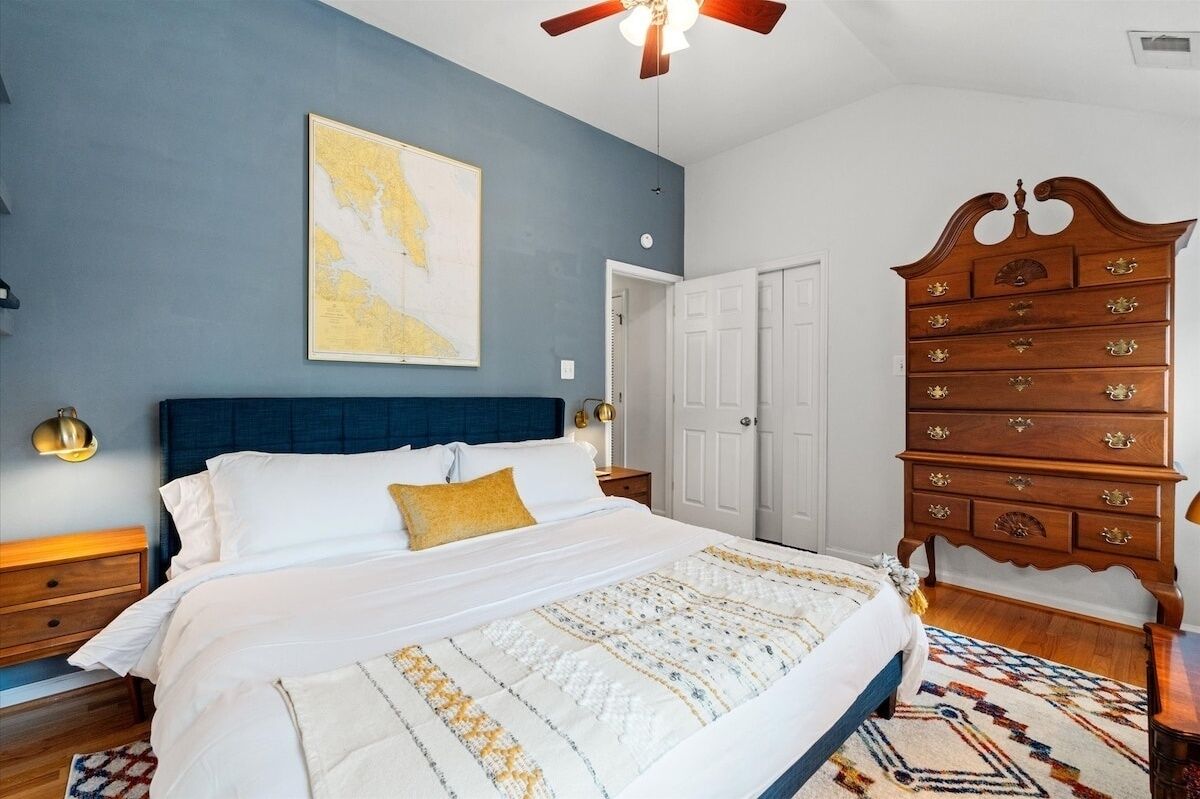 Ein Schlafzimmer mit einem großen Bett, einer Holzkommode, einer Karte an der Wand und einem Deckenventilator.