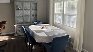 A dining area with a table set for four, a decorative cabinet, and a window with blinds. - Relaxing 3-Bedroom Getaway in Peaceful Cades – Sleeps 8 (Cades)