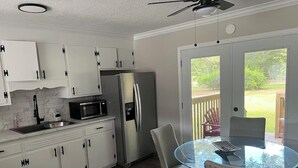 A modern kitchen with white cabinets, a stainless steel refrigerator, and a glass dining table with chairs. - Relaxing 3-Bedroom Getaway in Peaceful Cades – Sleeps 8 (Cades)