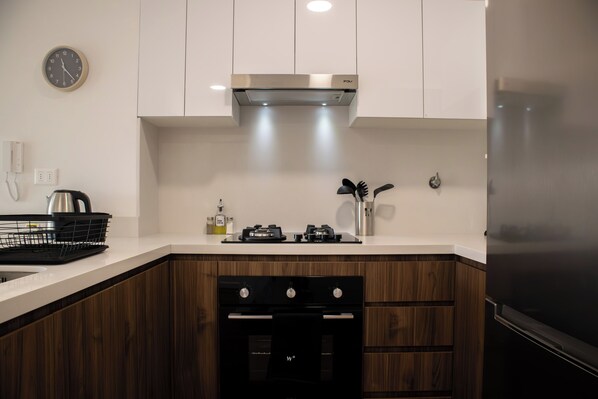 A modern kitchen with a black stove, stainless steel appliances, and wooden cabinets.