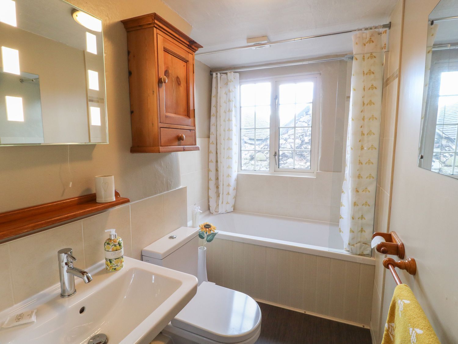 A bathroom with a sink, toilet, and window with curtains.
