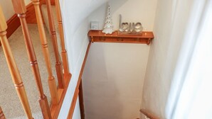 Eine Holztreppe mit einer weißen Wand und einem Regal, auf dem ein kleiner, weißer Weihnachtsbaum und ein Schild mit der Aufschrift 'love' stehen.