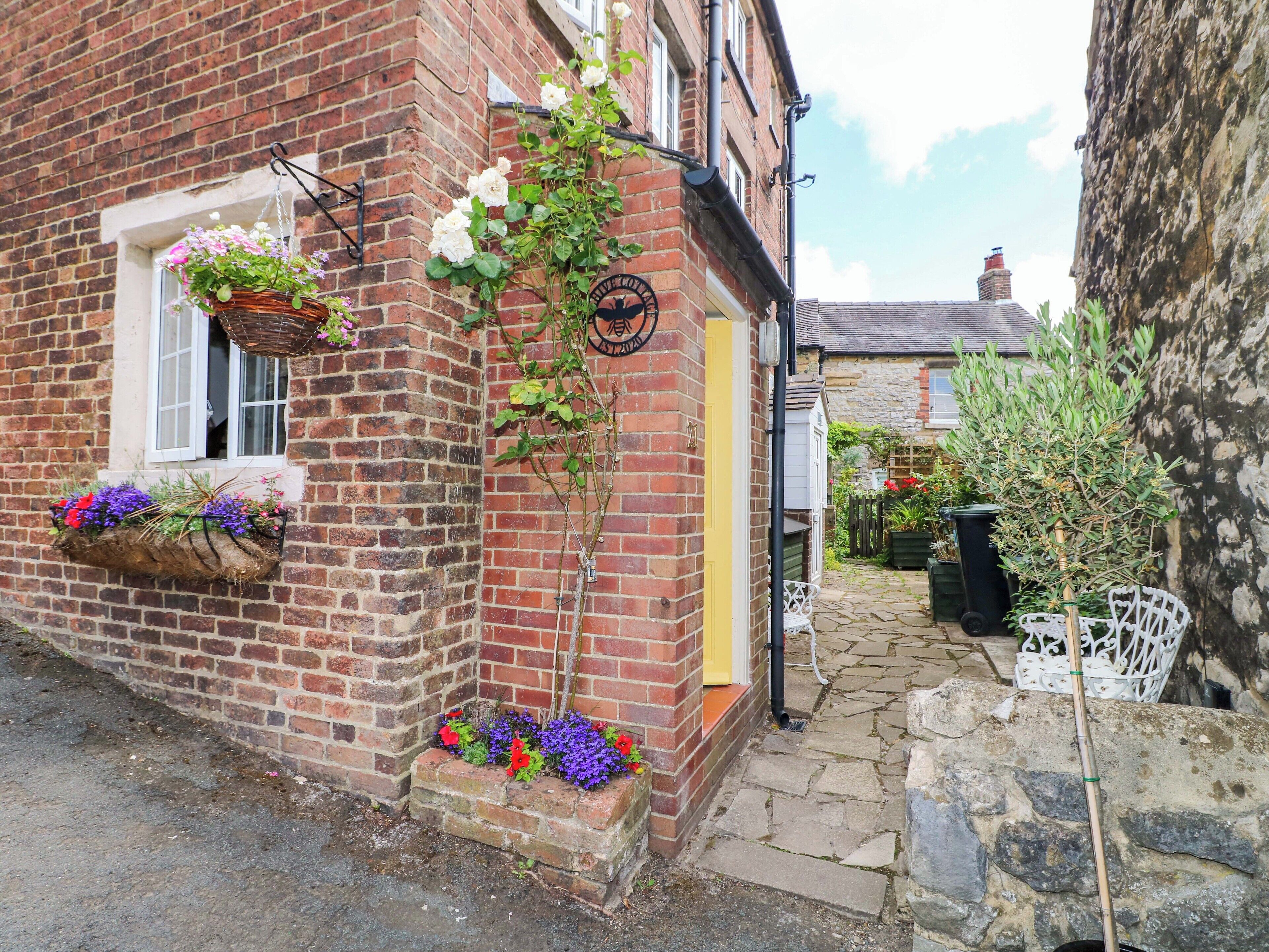 A brick building with flower boxes, a small garden, and a stone pathway.