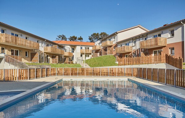 Zona de piscina con balcones de madera y cielo despejado.