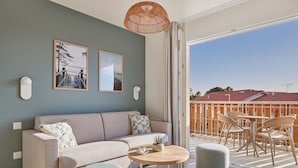 A modern living room with a sofa, a round coffee table, and a balcony with outdoor seating.