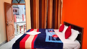 A hotel room with a bed, orange walls, and a view of a balcony with buildings. - Hotel Him Deep Uttarkashi (Bhatwari)