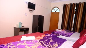 A hotel room with two beds, a TV, a wardrobe, and a window with curtains. - Hotel Him Deep Uttarkashi (Bhatwari)