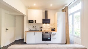 Una cocina moderna con gabinetes blancos, una campana extractora negra y un amplio ventanal que proporciona luz natural.