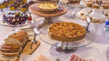 Un buffet proposant une variété de plats, notamment une quiche, du pain et différentes sortes de viandes.