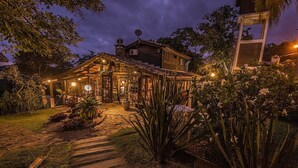 A wooden house with a covered porch and a stone pathway leading to the entrance. - Pousada Morada dos Bougainvilles (Imbituba)