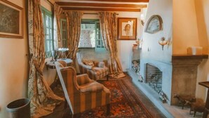 Una camera tradizionale con camino, tende a motivi decorativi e soffitto in legno.
