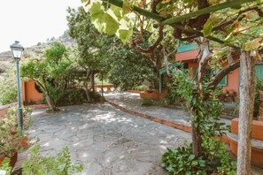 A stone pathway leading to a building with a green roof, surrounded by greenery and a lamp post. - Cloty Holiday Rental by VillaGranCanaria (Vega de San Mateo)