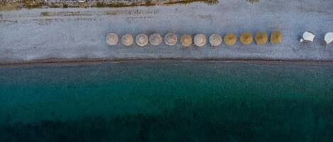 An aerial view of a beach with a row of circular objects, possibly umbrellas, aligned along the shoreline.