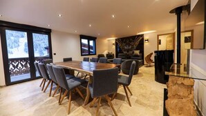 A spacious dining area with a large wooden table surrounded by chairs, a cozy seating area with sofas, and a stone fireplace. - Montaska - Chalet La Plagne - 7 Suites - Jacuzzi / Sauna (La Plagne Tarentaise)