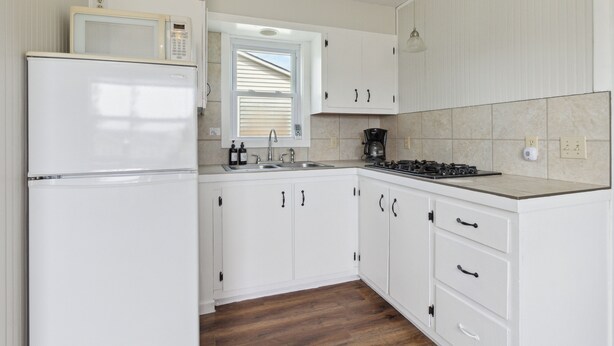 A kitchen with white cabinets, a refrigerator, a microwave, a sink, and a stove. - Cabin 9 / Pleasant Valley Resort / Hot Tub / Sauna / BBQ (Arcadia)