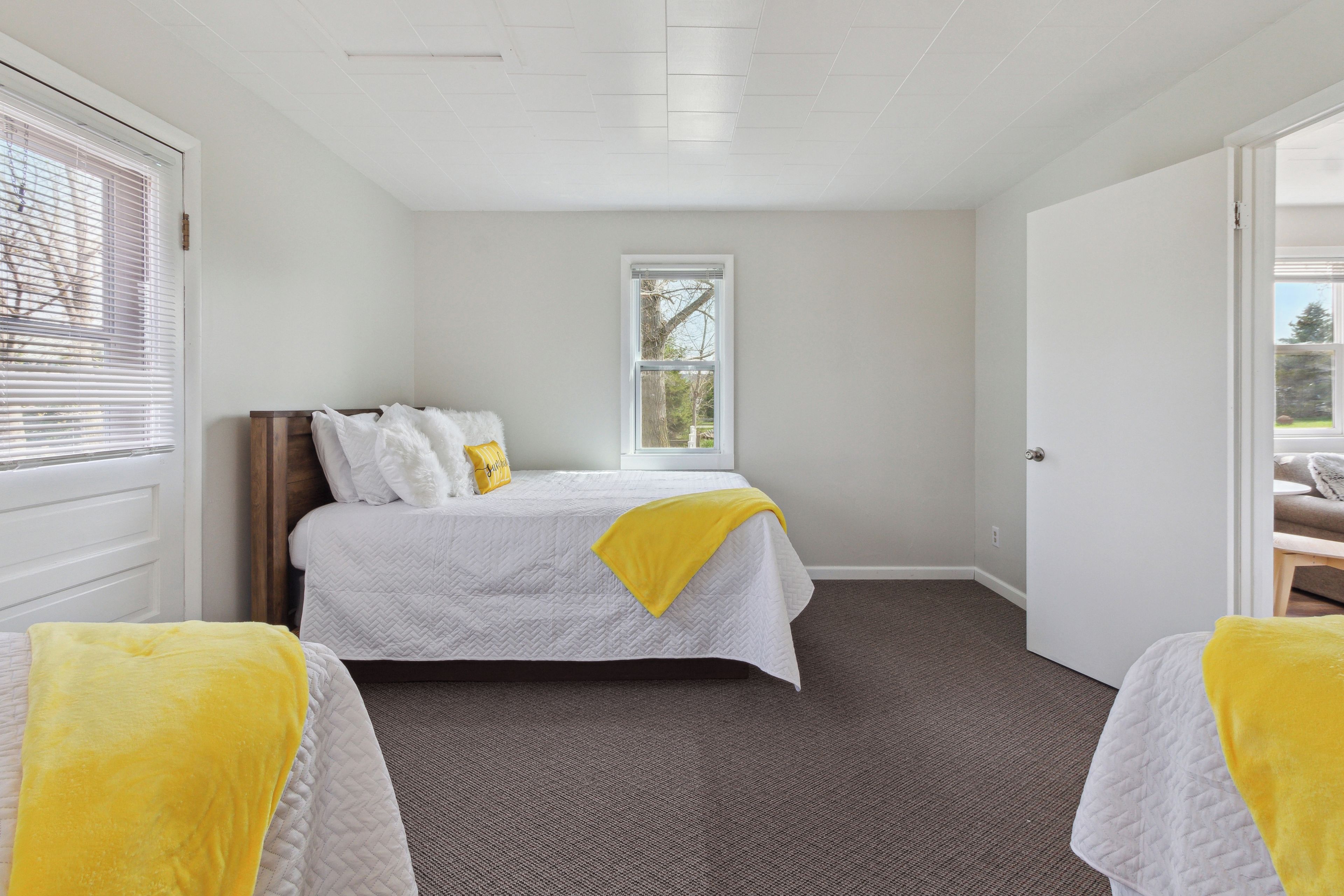 A bedroom with a bed, a window, and a door.