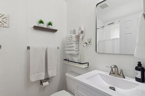 A bathroom with a white sink, a mirror, a towel rack, a toilet, and a hairdryer.