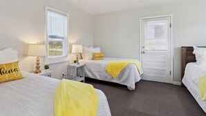 Une chambre d’hôtel avec deux lits, une porte et une fenêtre avec des stores.