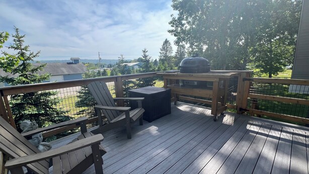 A wooden deck with a grill, chairs, and a table.