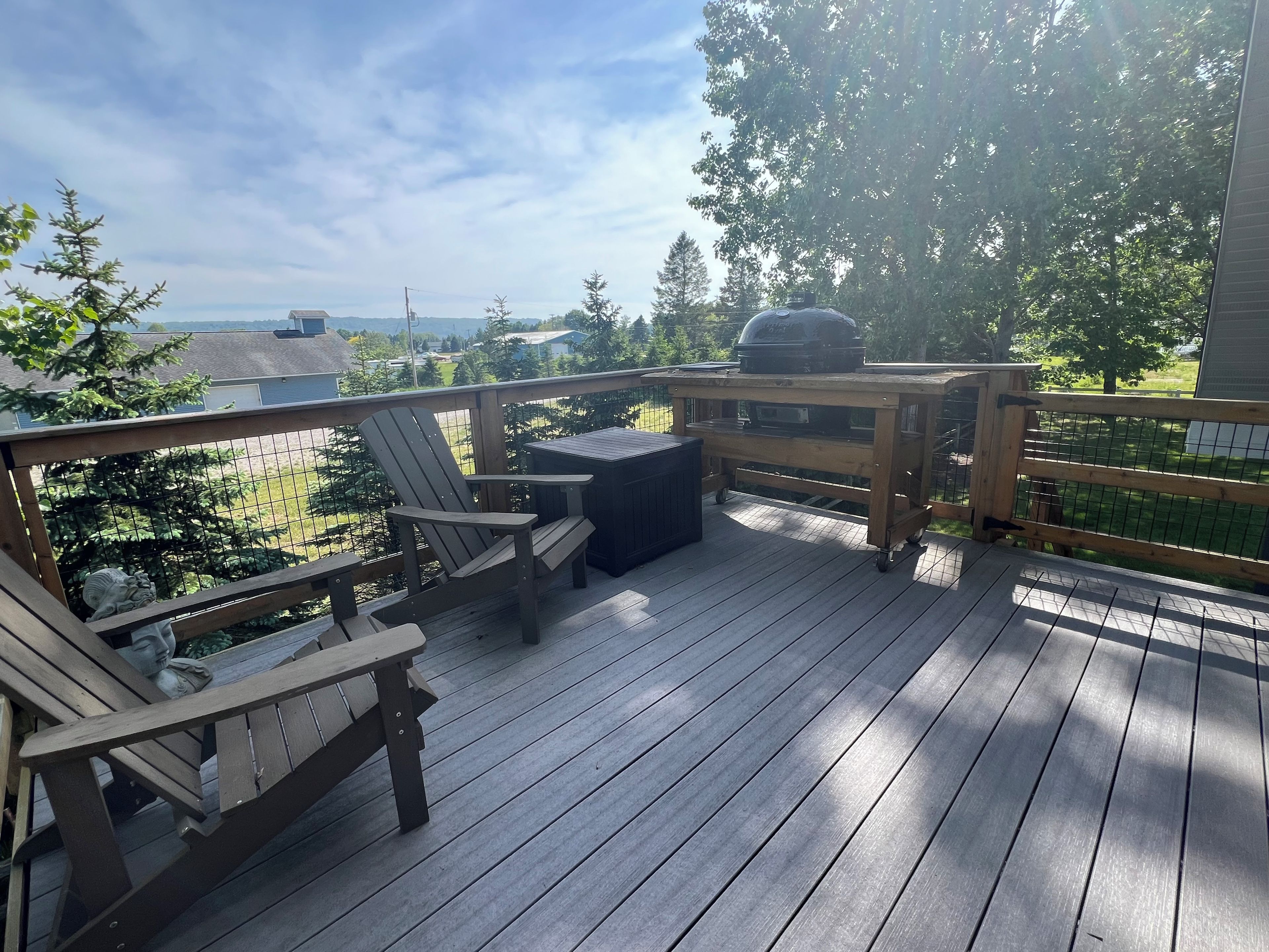 A wooden deck with a grill, chairs, and a table.