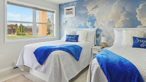 A bedroom with two beds, a large window, and a mural of clouds on the wall. - Deluxe Double Studio 6 (Arcadia)