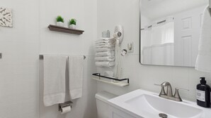 Ein Badezimmer mit Waschbecken, Spiegel, Handtuchhalter, Toilette und Fön.