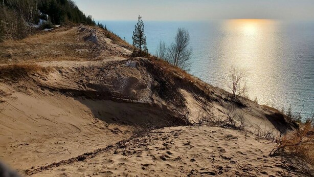 Eine Küstenlandschaft mit Sandstrand, spärlicher Vegetation und freiem Blick auf den Ozean.