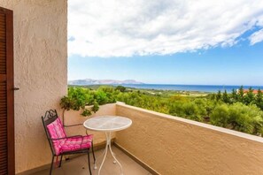 Un balcon agrémenté d’une chaise et d’une table, offrant une vue sur la verdure et les collines lointaines.