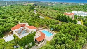 A villa with a swimming pool, surrounded by lush greenery and a view of the sea. - Villa Armi (Pirgos)